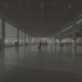 Wide view of a quiet international airport terminal with travelers in the distance.