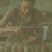 African American woman mixing dried herbs in a bowl at a kitchen table.